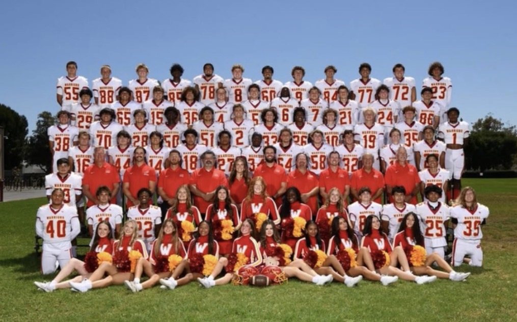 The 2026 Woodbridge Warriors varsity football team, coaching staff, and song and cheer squad in team photo formation on the field at Woodbridge High School
